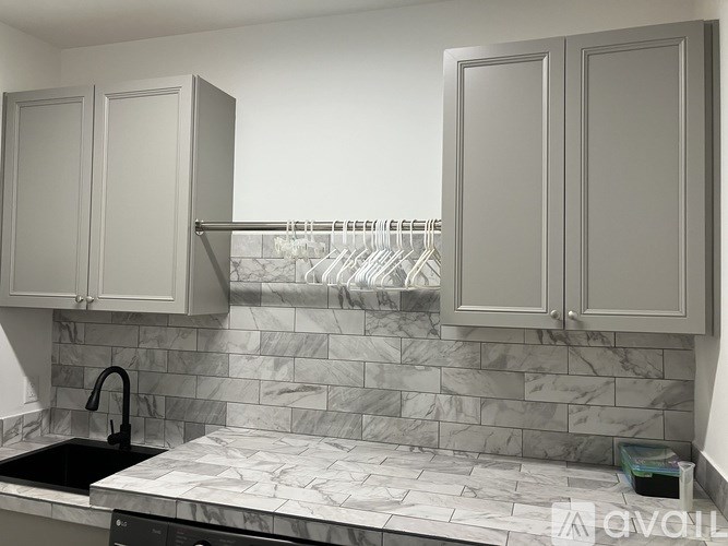 A kitchen with marble countertops and grey cabinets.