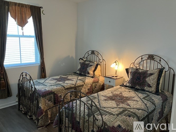 Two twin beds with matching quilts and pillows are in a room with a window.