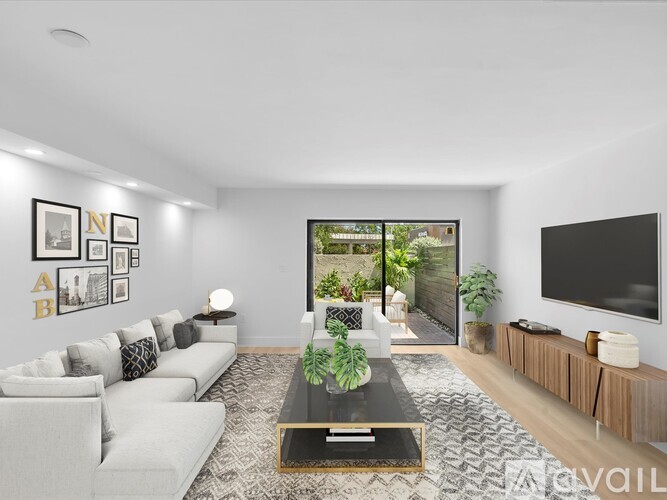 A living room with a white sofa, a coffee table, and a flat screen TV mounted on the wall.