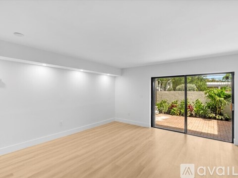 A spacious room with wooden flooring and a view of a garden through a glass door.