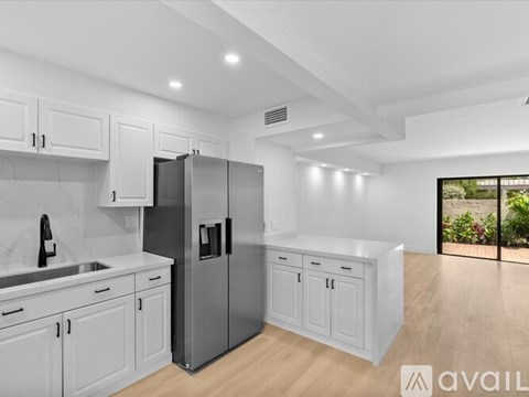 A modern kitchen with white cabinets and a stainless steel refrigerator.