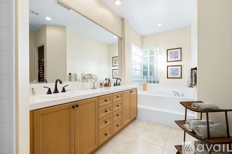 A bathroom with a large mirror, two sinks, and wooden cabinets.