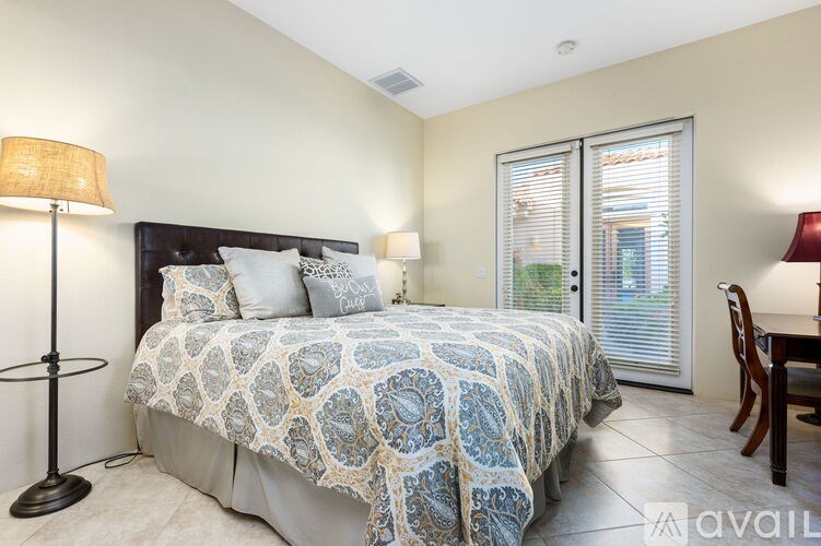 A bedroom with a bed, two lamps, and a chair.