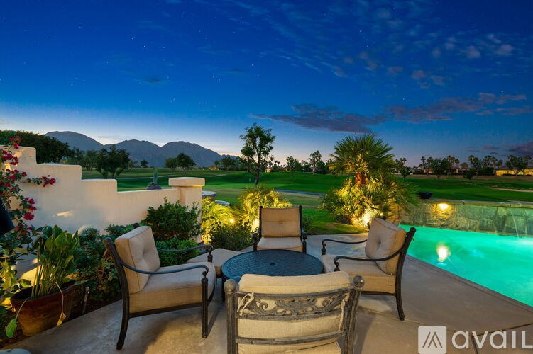 A poolside patio with chairs and a table is set for an evening of relaxation.