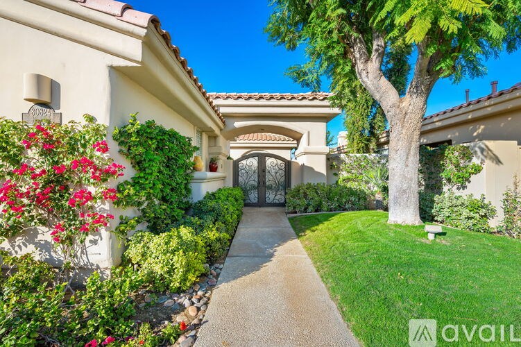 A house with a tree in front and a pathway leading to the entrance.