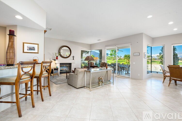 A spacious living room with a fireplace and a dining area with chairs.