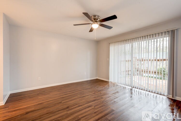 A room with a ceiling fan and wooden flooring.