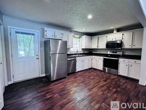 A kitchen with white cabinets and a wooden floor.