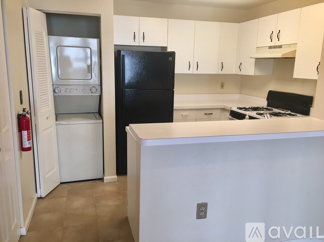 A kitchen with a black refrigerator and white cabinets.