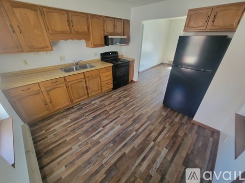 A kitchen with wooden cabinets and a black refrigerator.