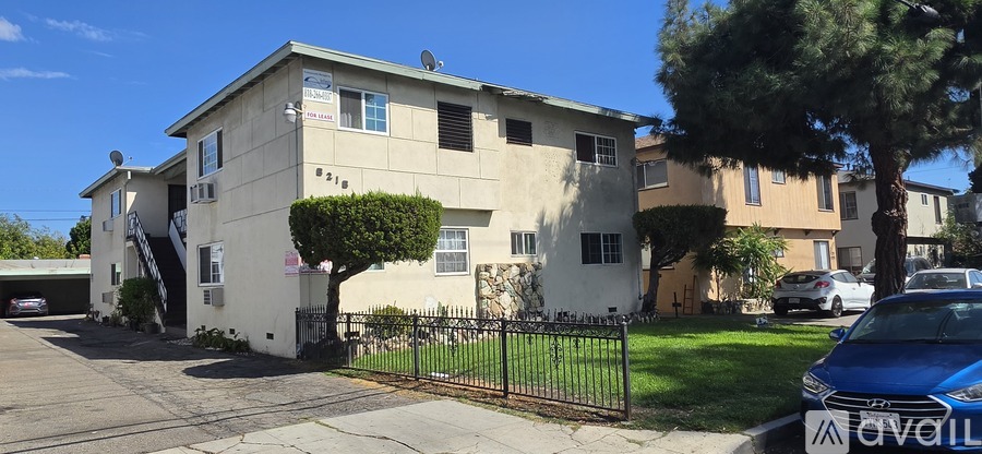 A two-story building with a beige exterior and a black fence in front.
