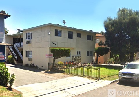 A two-story building with a beige exterior and a black fence in front.