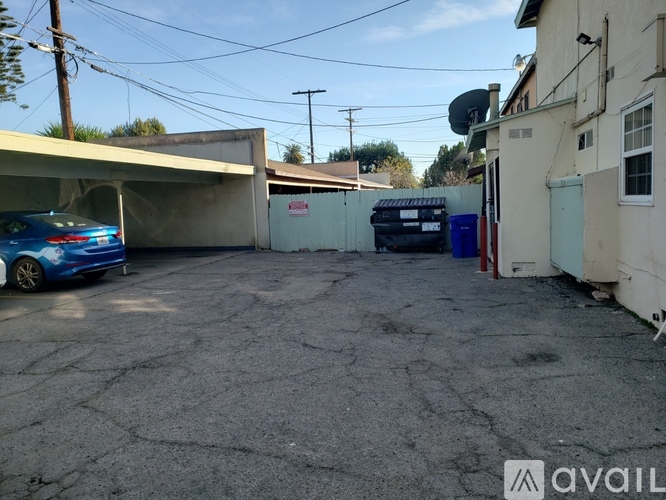 A blue car is parked in a driveway with a garage door open.