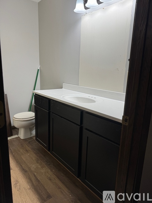 A bathroom with a toilet, sink, and black cabinetry.