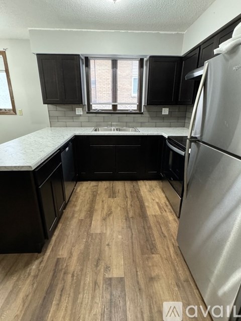 A kitchen with black cabinets and a wooden floor.