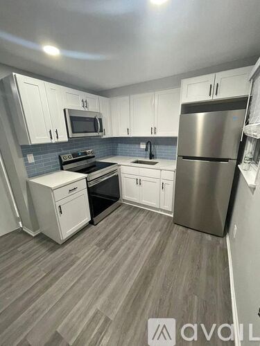A kitchen with a stove top oven, microwave, refrigerator, and sink.