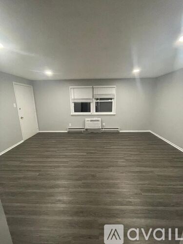 A room with wooden flooring and a window with blinds.