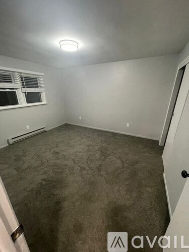 A room with a carpeted floor and a window with blinds.