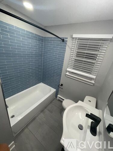 A white sink with a black handle is in a bathroom with blue tiles.