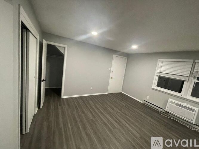 A room with a window and a wall-mounted air conditioning unit.