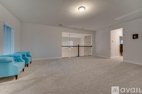 A spacious living room with a blue sofa and a white ceiling.