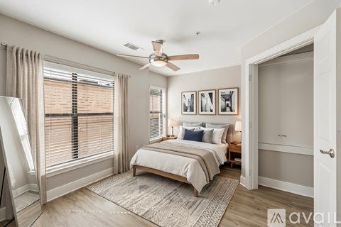 A bedroom with a bed, desk, and window with blinds.