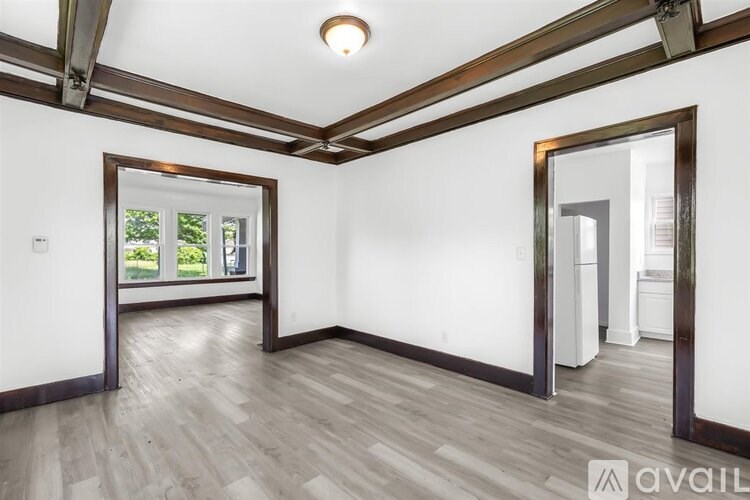 A room with wooden floors and white walls, with a window and a door visible.