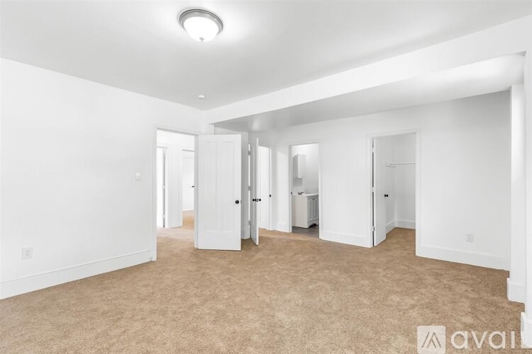 A large, empty room with carpeted flooring and white walls.
