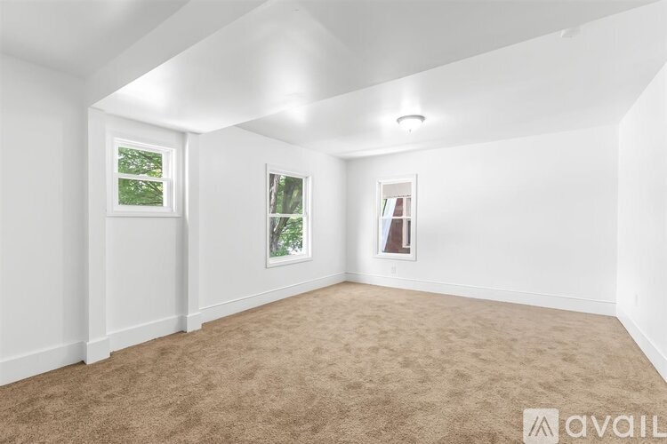 A room with carpeted floor and two windows.