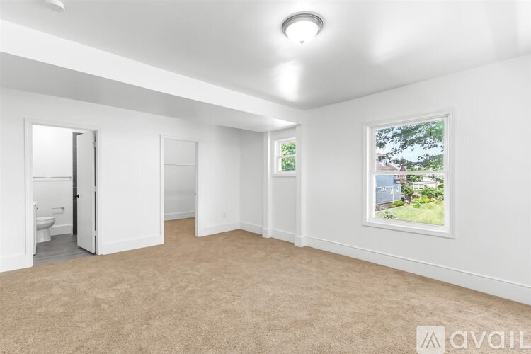 A room with a carpeted floor and a window showing a tree and a house outside.