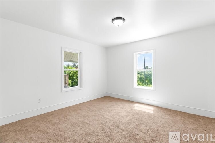 A room with two windows and a carpeted floor.