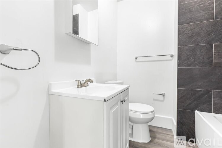 A white bathroom with a toilet, sink, and mirror.