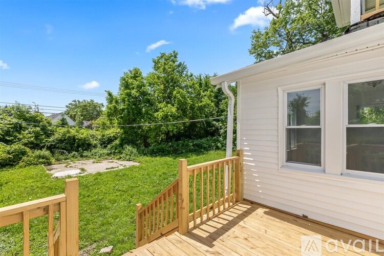 A wooden deck with a railing and a window overlooking a green lawn.