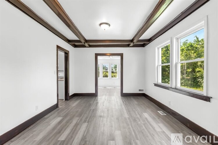A spacious room with wooden floors and white walls.