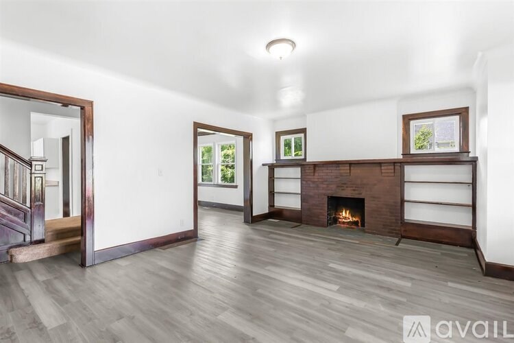 A spacious living room with a fireplace and a staircase.