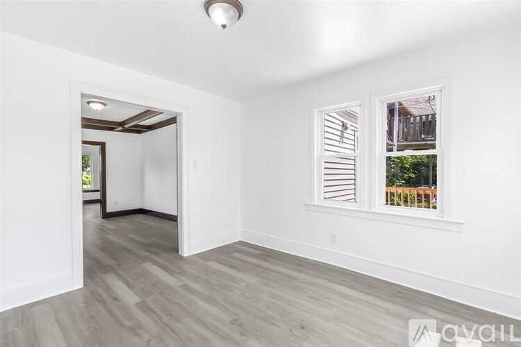 A room with a window and a doorway leading to another room.