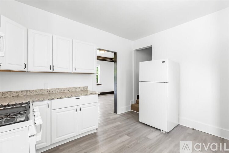 A kitchen with white cabinets and a white fridge.