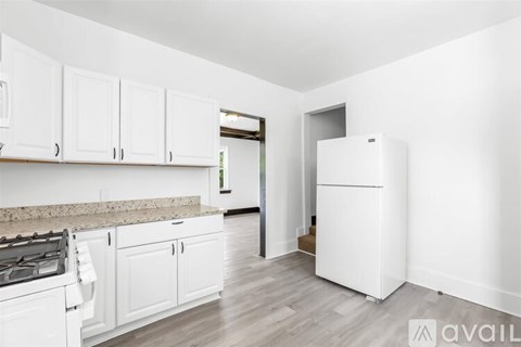 A kitchen with white cabinets and a white fridge.