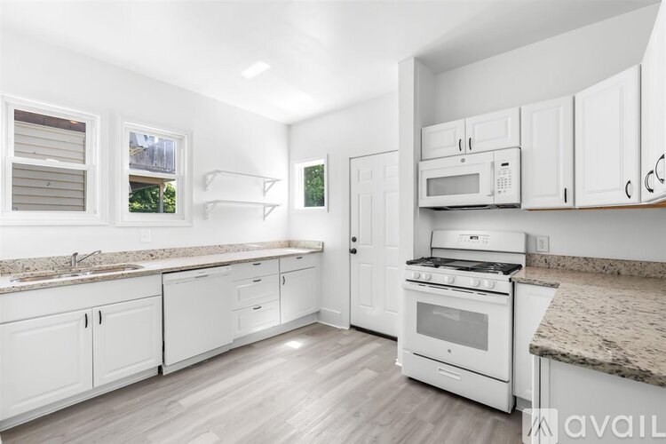 A kitchen with white cabinets and a granite countertop.