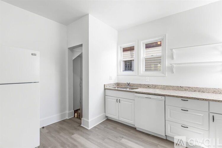 A kitchen with white cabinets and a refrigerator.