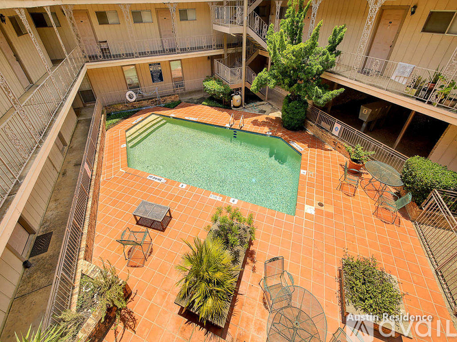 A small pool surrounded by chairs and plants in a courtyard.