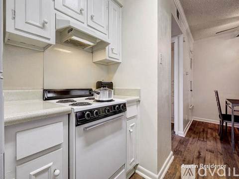 A white kitchen with a stove top oven and a white cabinet.