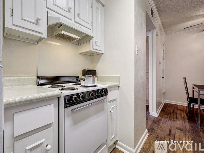 A white kitchen with a stove top oven and a white cabinet.