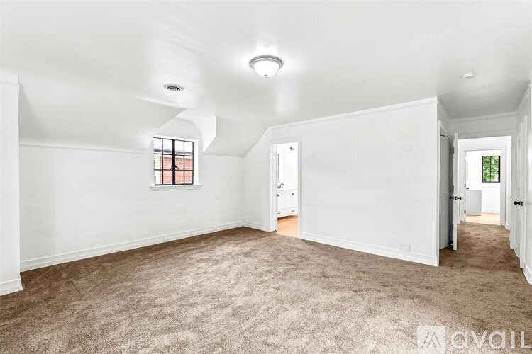 A spacious room with a carpeted floor and a window with bars.