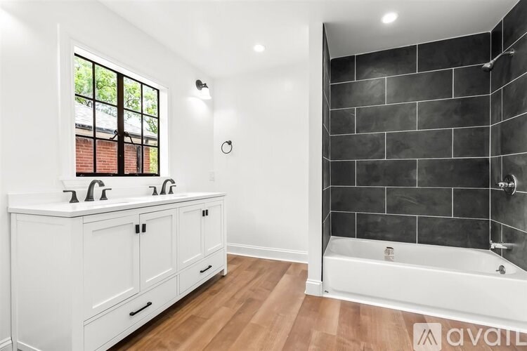 A bathroom with a white cabinet and a black tiled shower.