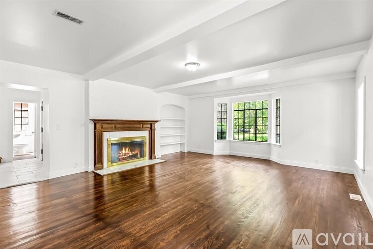 A large, empty room with a fireplace and wood flooring.