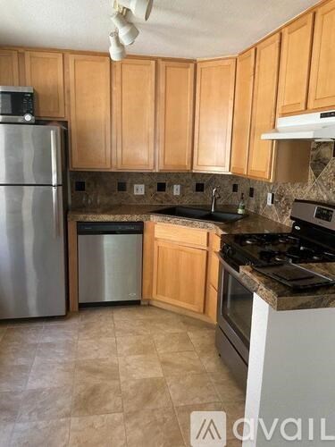 A kitchen with wooden cabinets and a stainless steel refrigerator.