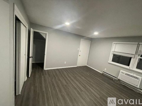 A room with a window and a wall-mounted air conditioning unit.