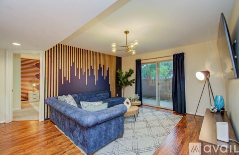 A modern living room with a blue sofa and a wooden wall panel.