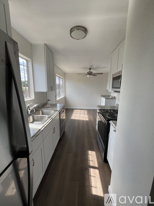 A kitchen with white cabinets and a black fridge.